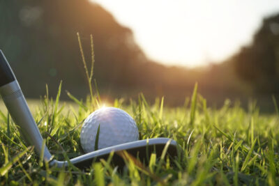 Blurred golf ball and golf club in beautiful golf course at sunset background.