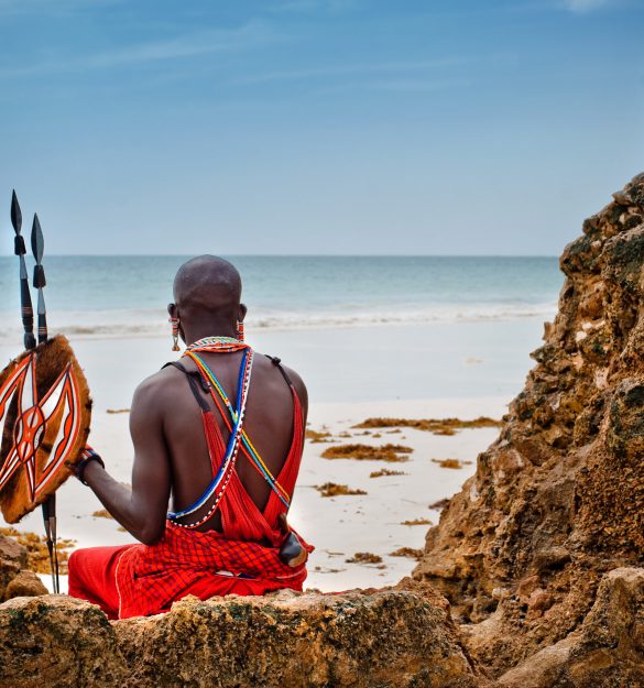 African man of the Maasai tribe in Kenya sits on the ocean and looks into the distance. The flavor of the journey. Travel Culture